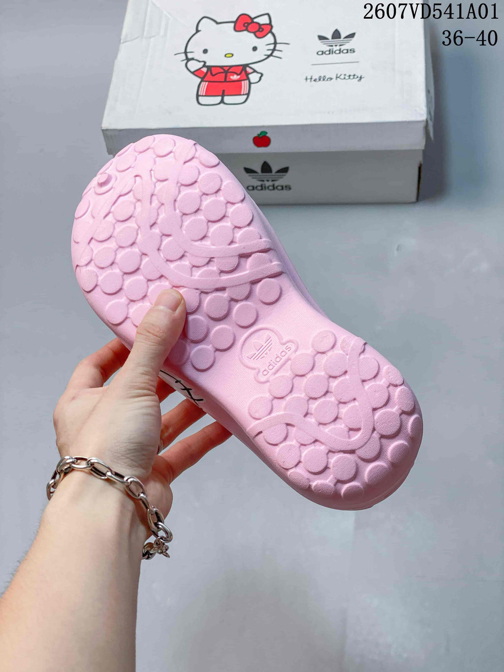 Underside of a pink clog showing its textured tread, with the adidas x Hello Kitty box in the background