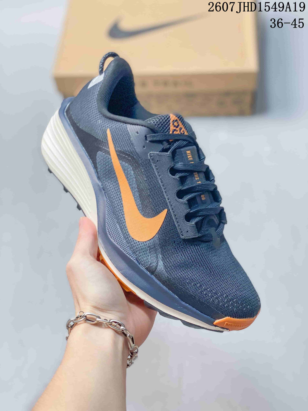 Dark Nike Zoom Fly 5 sneaker with a bright orange Swoosh, orange outsole accents, and a cream-colored midsole.