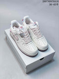 Pair of white Nike low-top sneakers with pale pink accents, decorative charm and code 2607ND976A16 visible above the shoes.