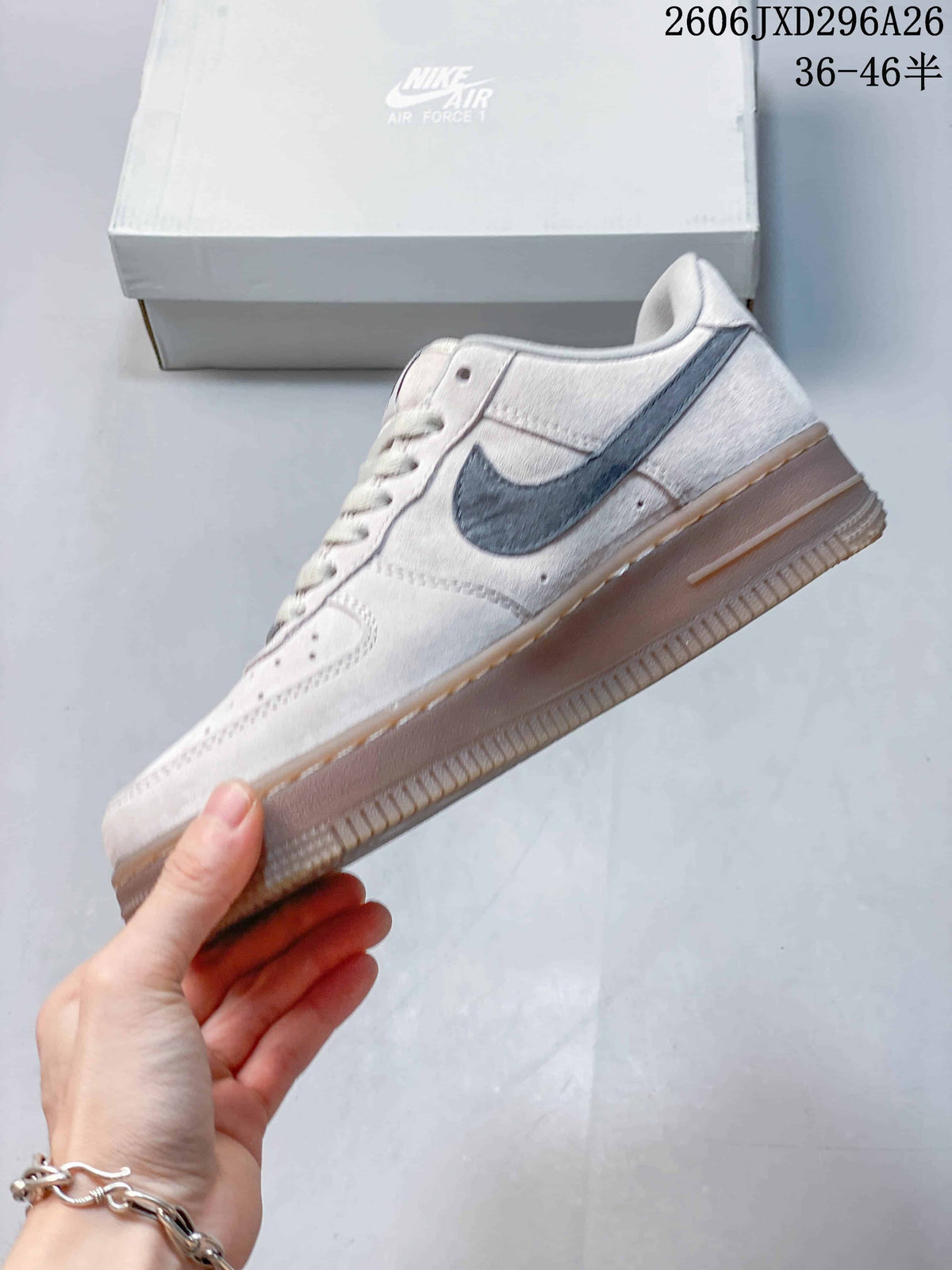 Side view of a light-colored low-top sneaker with a gray Swoosh and gum-tone sole