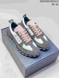 Pair of gray, white, and pink Dior Squash sneakers displayed on a shoebox, showing the pink laces, contrasting panels, and speckled midsoles.