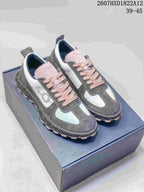 Pair of gray, white, and pink Dior Squash sneakers displayed on a shoebox, showing the pink laces, contrasting panels, and speckled midsoles.