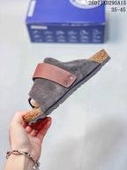Side profile showing the dark gray upper, brown adjustable strap with two visible rivets, cork-look midsole, and treaded outsole.