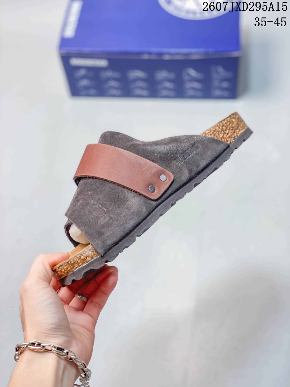 Side profile showing the dark gray upper, brown adjustable strap with two visible rivets, cork-look midsole, and treaded outsole.