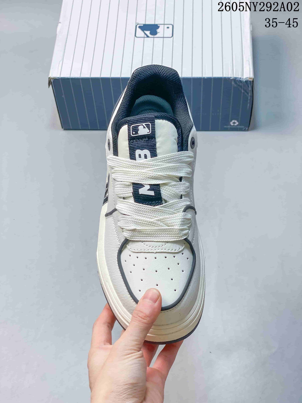 Top view of the sneaker showing white laces, a perforated toe area, dark trim, and tongue branding.