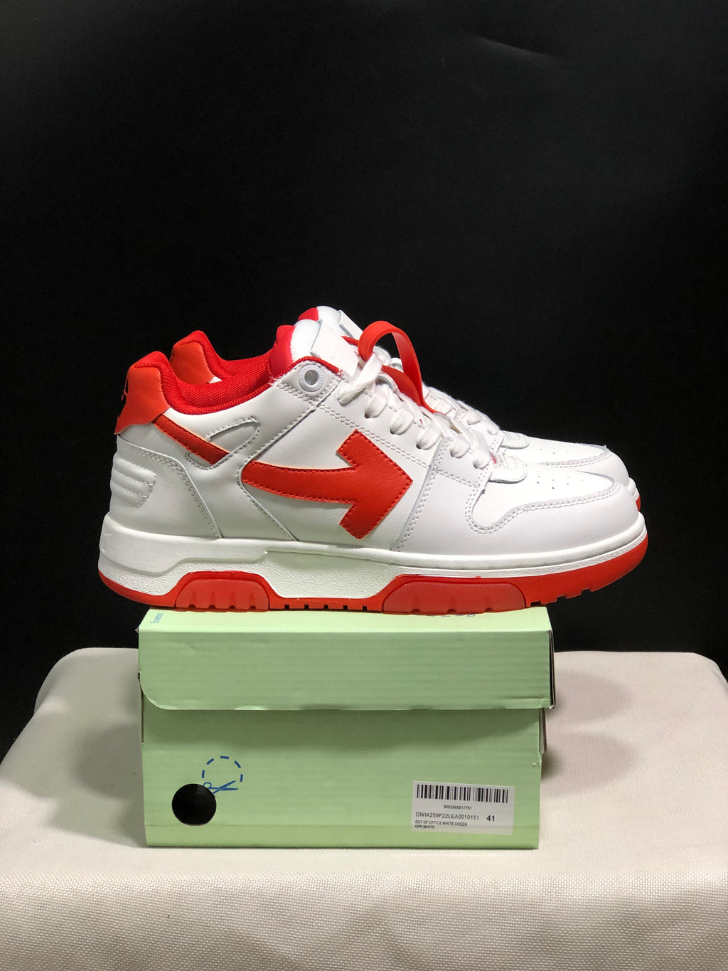 Side view of the white and red low-top sneakers showing the contrasting arrow detail and red outsole.