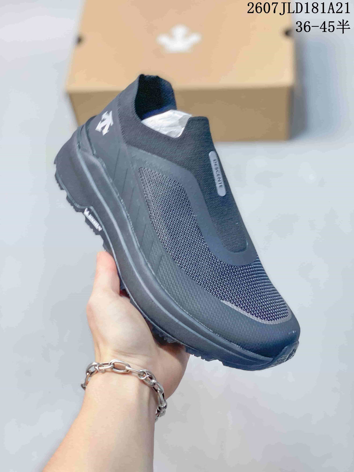 Angled side view of the black DESCENTE slip-on sneaker showing the upper, heel branding and outsole profile.