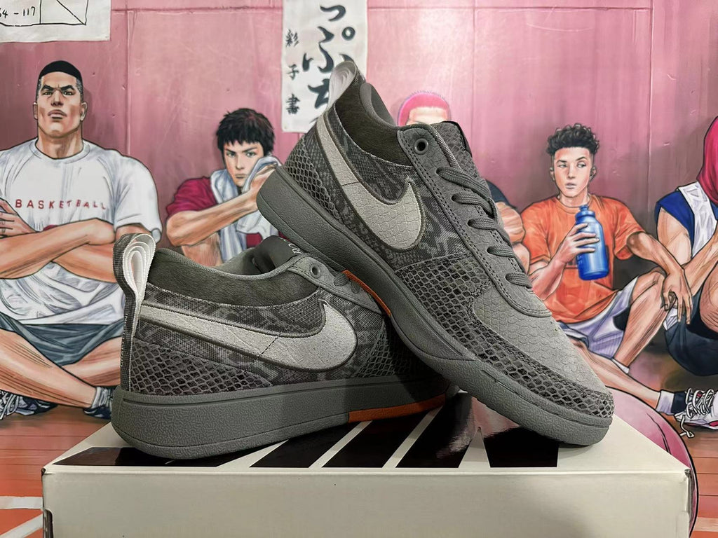 Pair of dark gray camouflage low-top Nike SB Dunk sneakers showing side details and orange outsole accents.