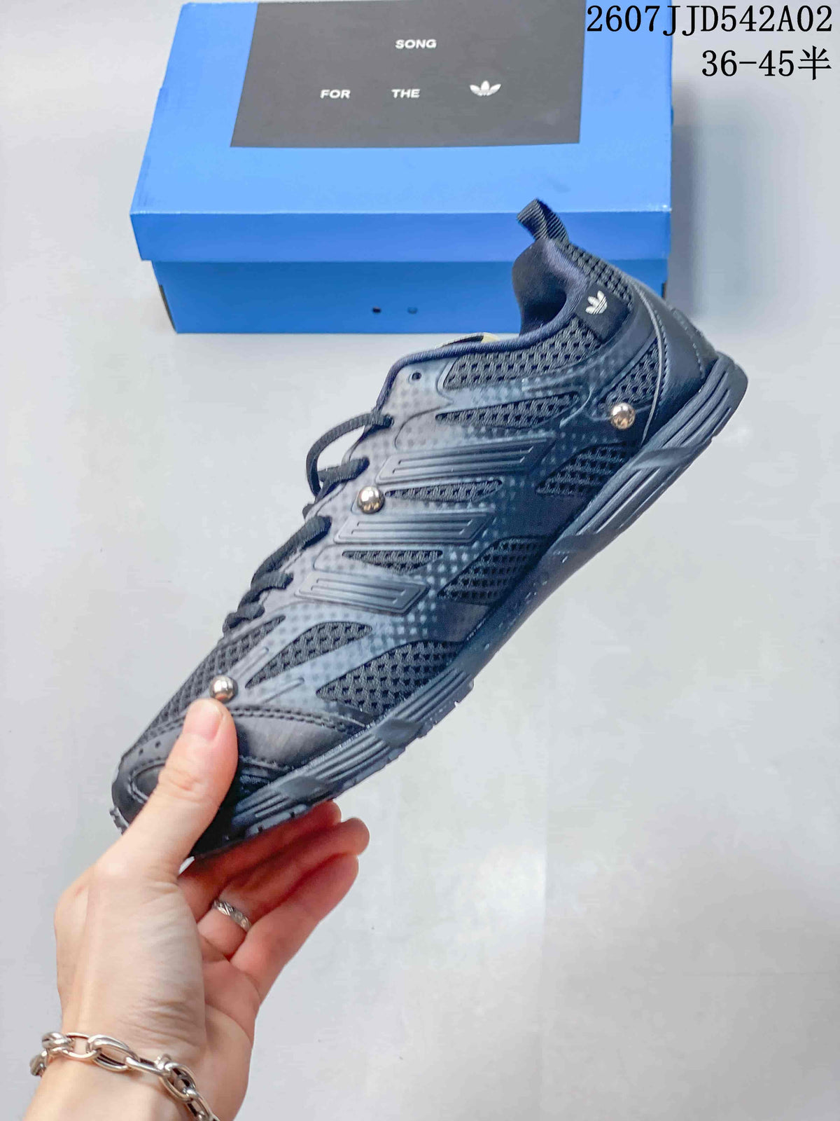 Side profile of a charcoal lace-up sneaker with layered side details