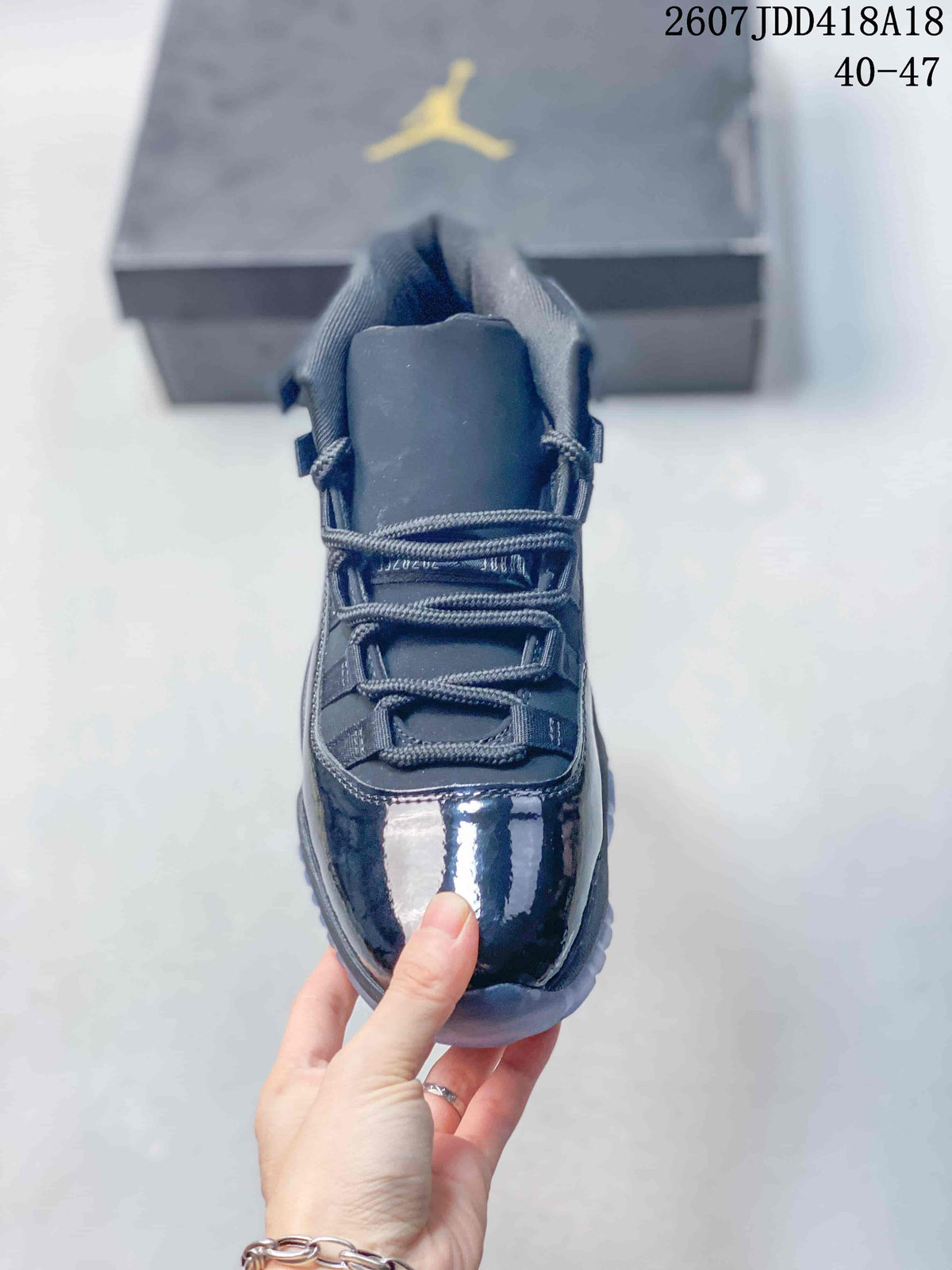 Front view of the sneaker showing the padded tongue, woven laces and glossy dark toe overlay.