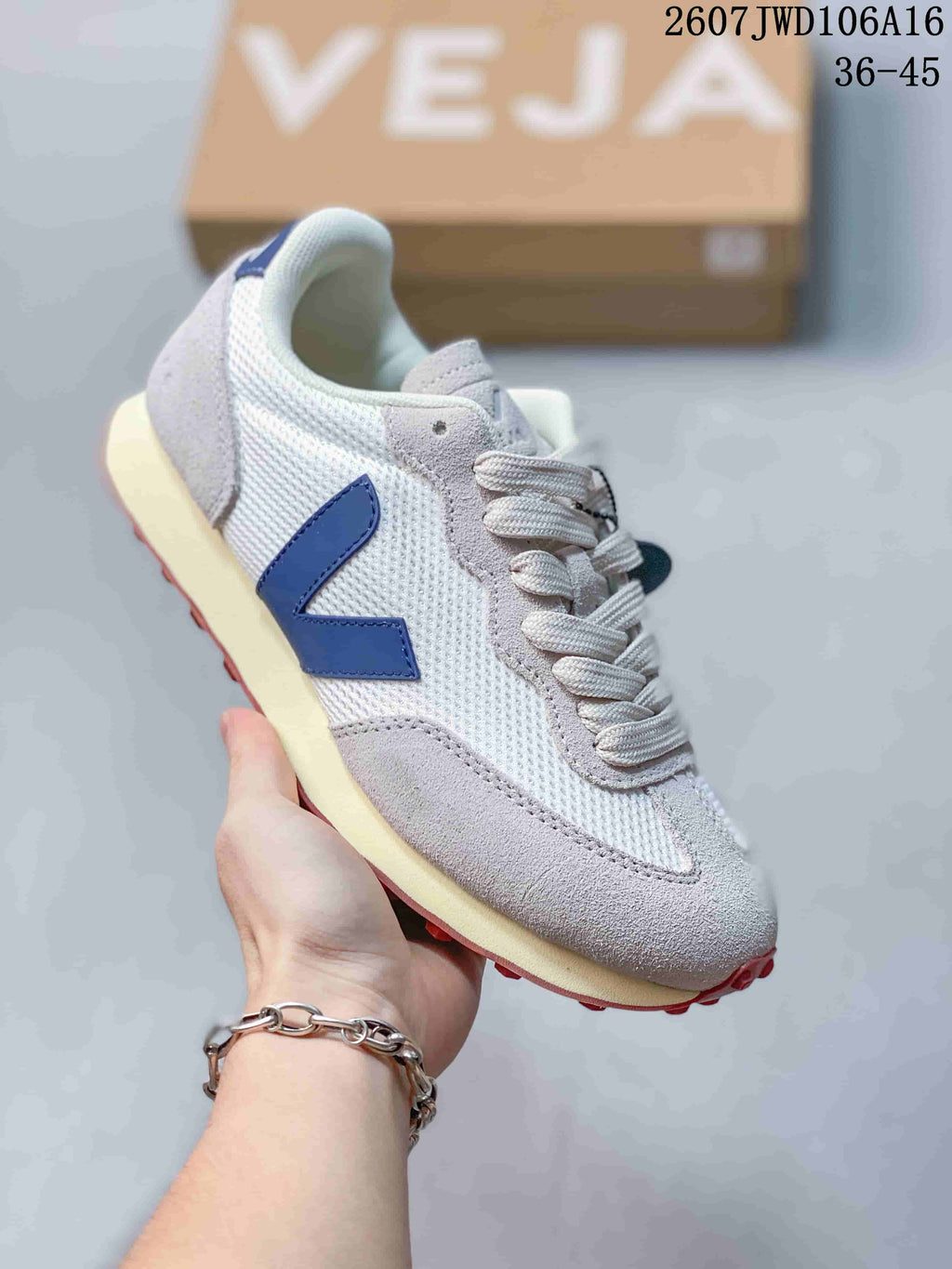 Angled side view of the white and blue VEJA sneaker highlighting the blue V logo, light overlays, cream midsole, and red outsole.