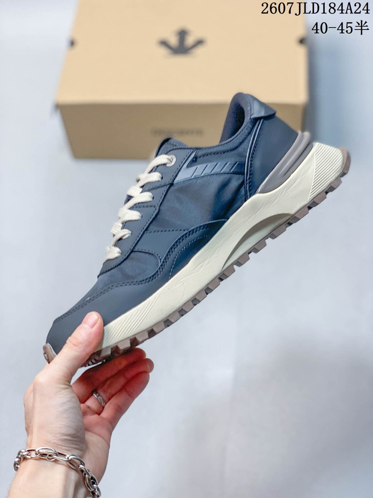 Side profile of the navy low-top sneaker showing layered upper panels, cream midsole and textured outsole.