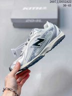 Side profile of the white and silver sneaker showing the large dark New Balance logo, layered panels, and textured outsole.