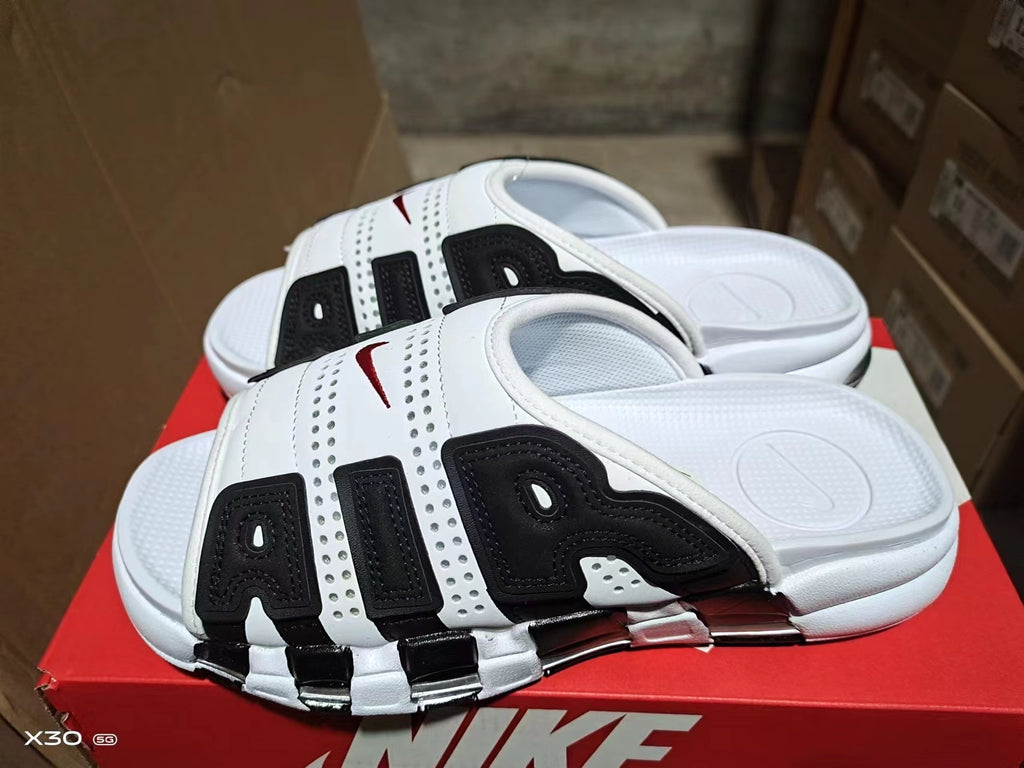 White and black Nike Air-style slide sandals with perforated upper, contrasting panels, and segmented outsole.