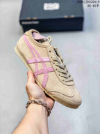 Angled side view showing the beige and pink color combination, layered side stripes, and textured sole.