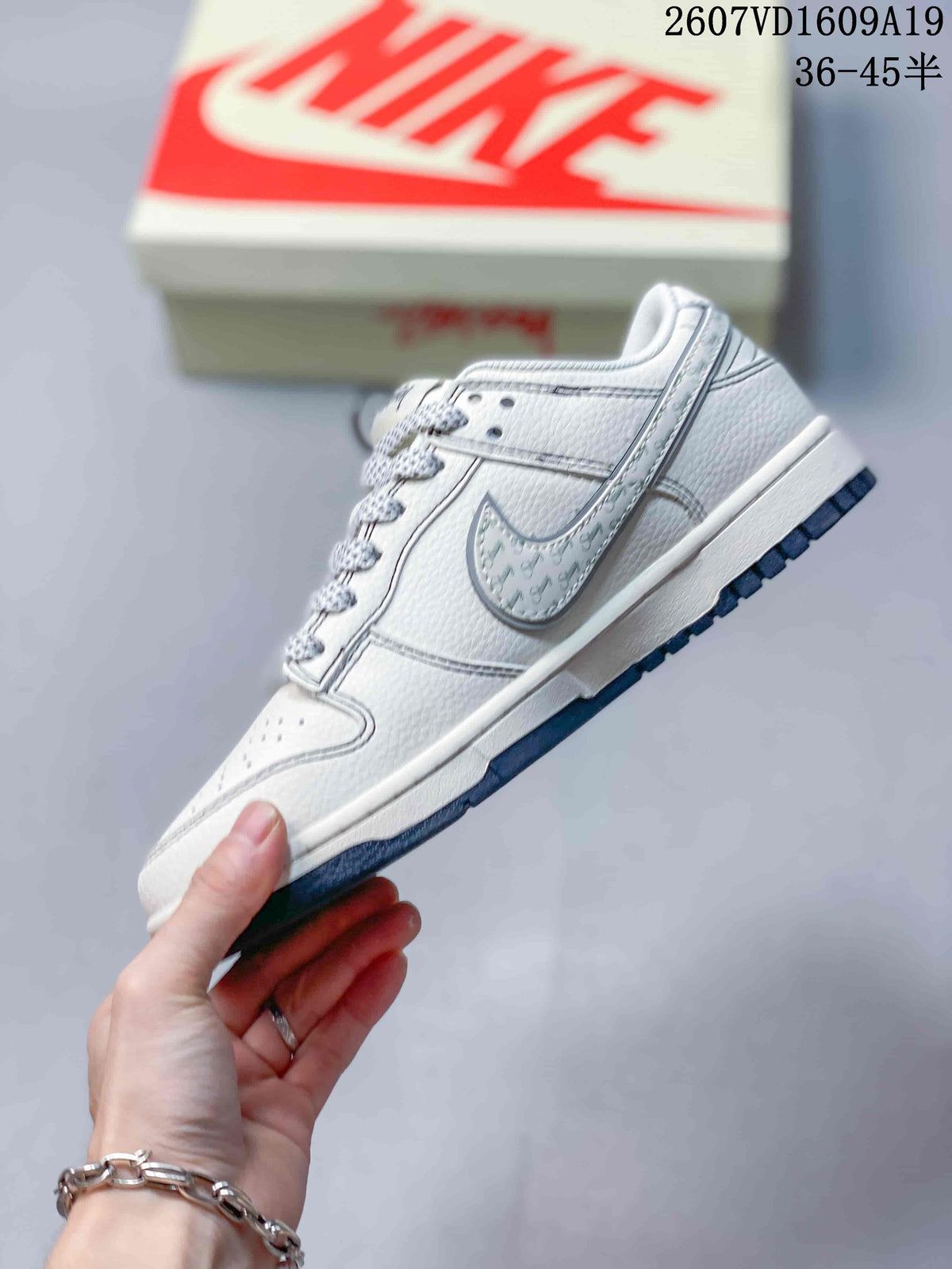 Side profile of a white low-top sneaker with a contrasting outlined swoosh, perforated toe box and navy outsole.