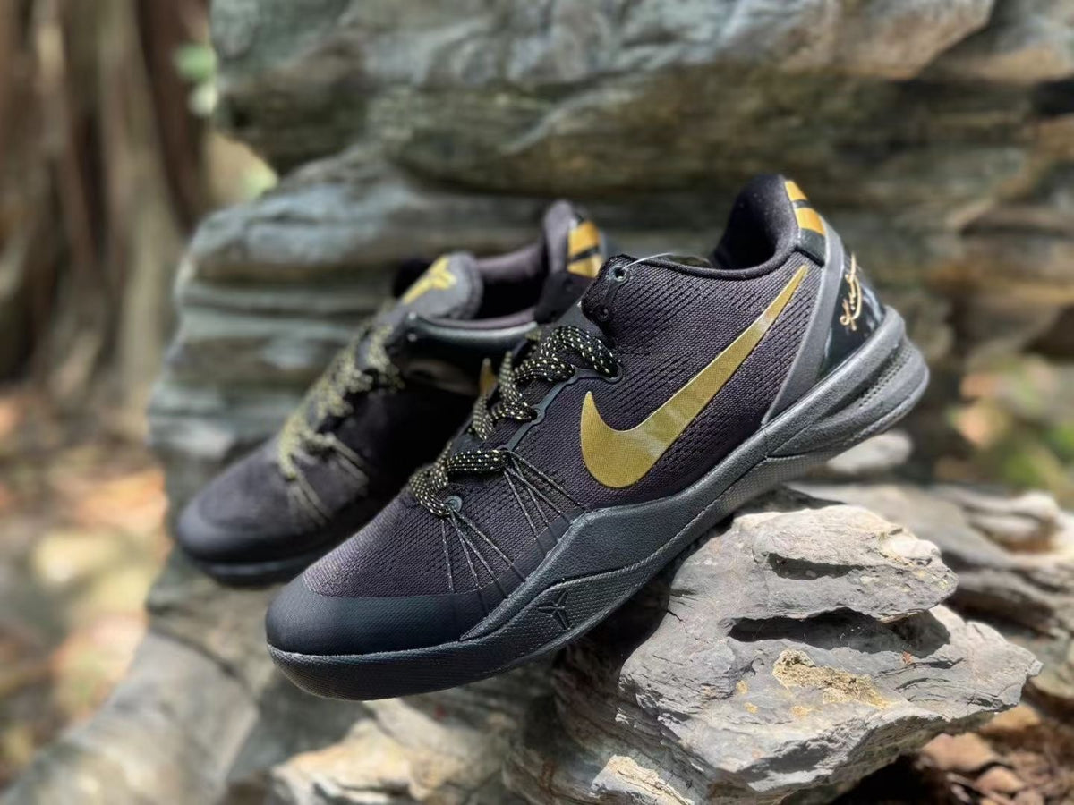 Angled front-side view of the black and gold sneaker pair with Kobe details visible at the heels.