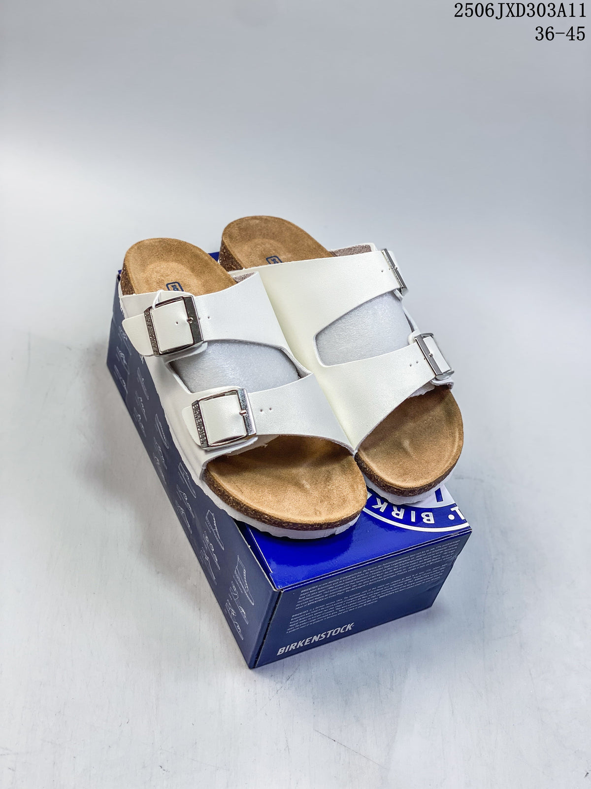 Pair of white two-strap slide sandals displayed on a blue box