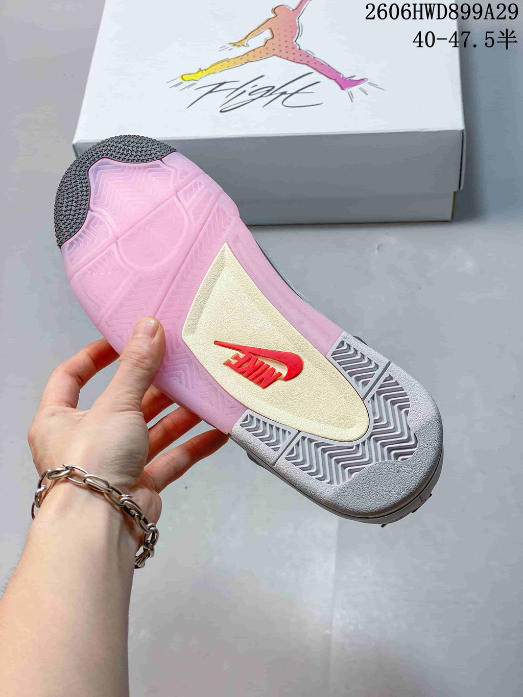 Underside of a sneaker showing a pink outsole, dark tread sections, and a contrasting central panel.