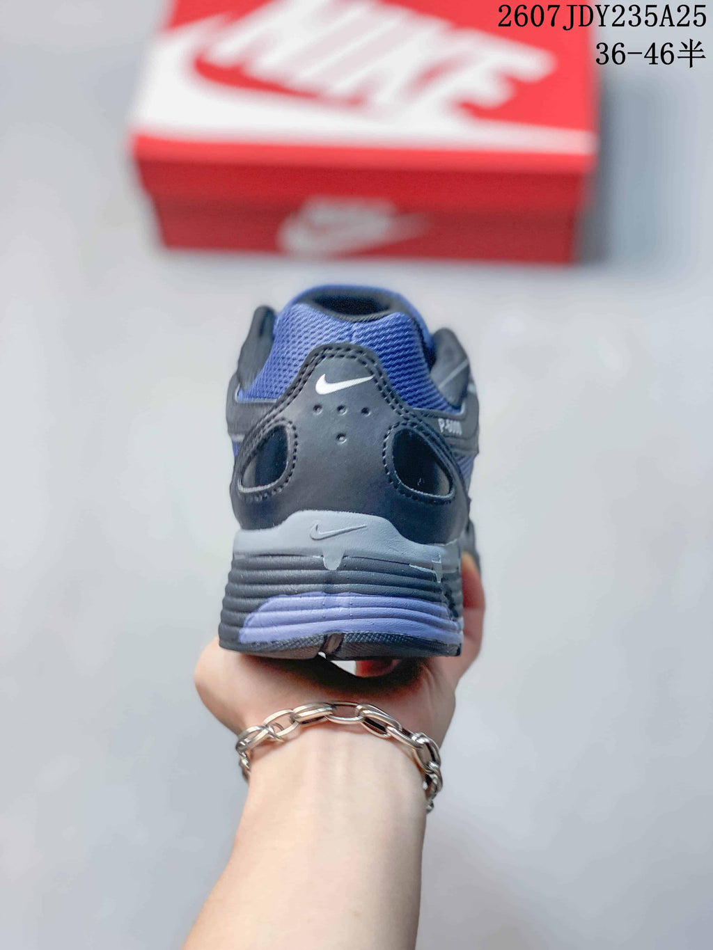 Rear view of a blue and dark gray Nike P-6000 sneaker showing the heel branding, layered heel structure and outsole.