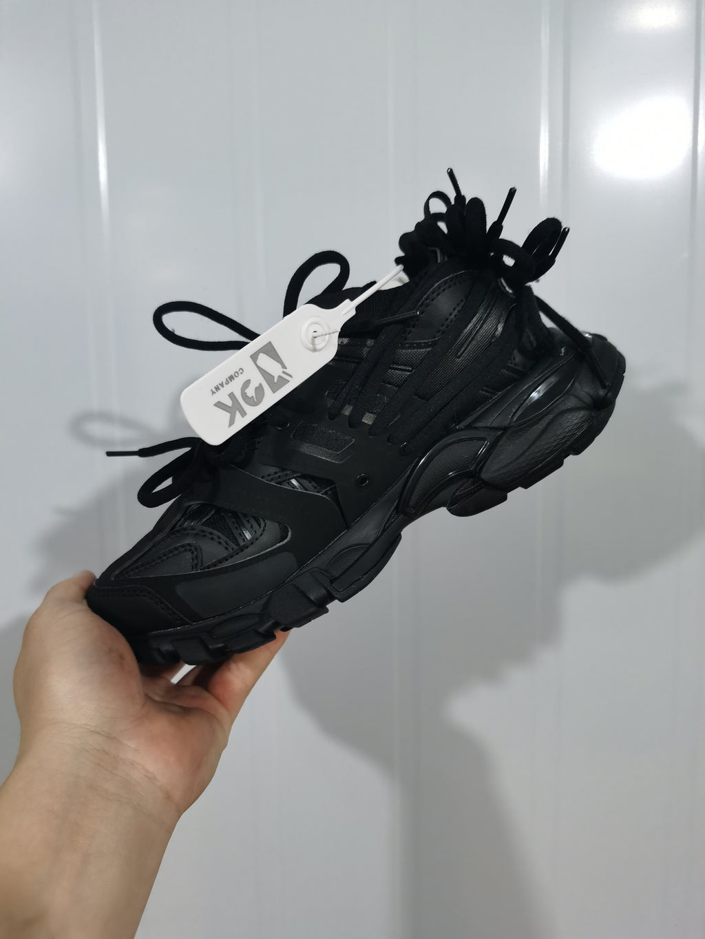 Black chunky lace-up sneaker shown from a front three-quarter angle with layered panels and a thick outsole.