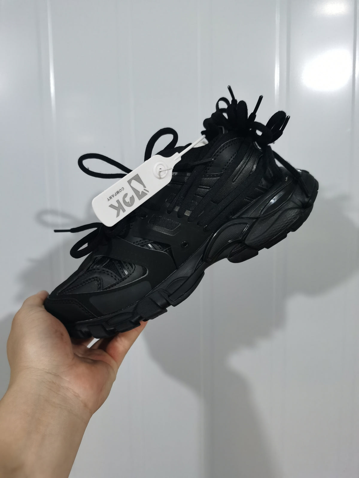 Black chunky lace-up sneaker shown from a front three-quarter angle with layered panels and a thick outsole.