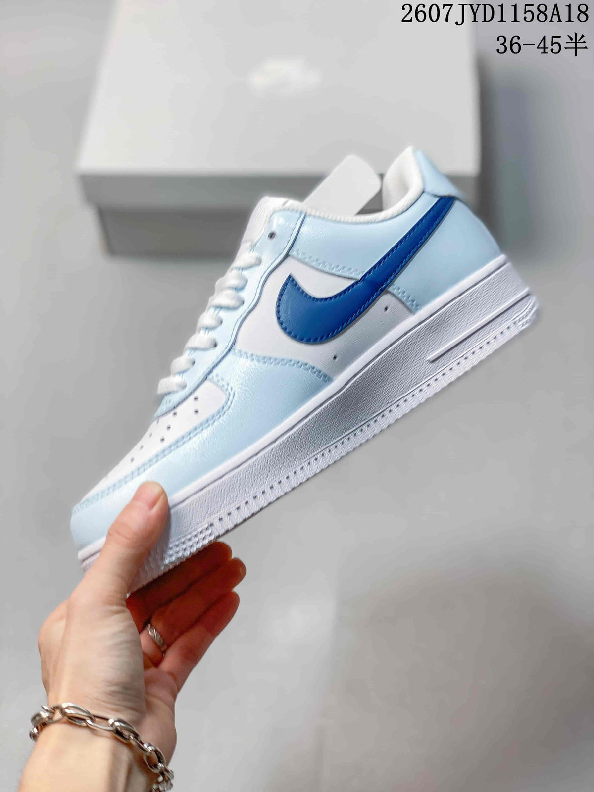 Side profile of the low-top sneaker showing the dark blue Swoosh, light blue overlays, white midsole, and perforated upper panels.