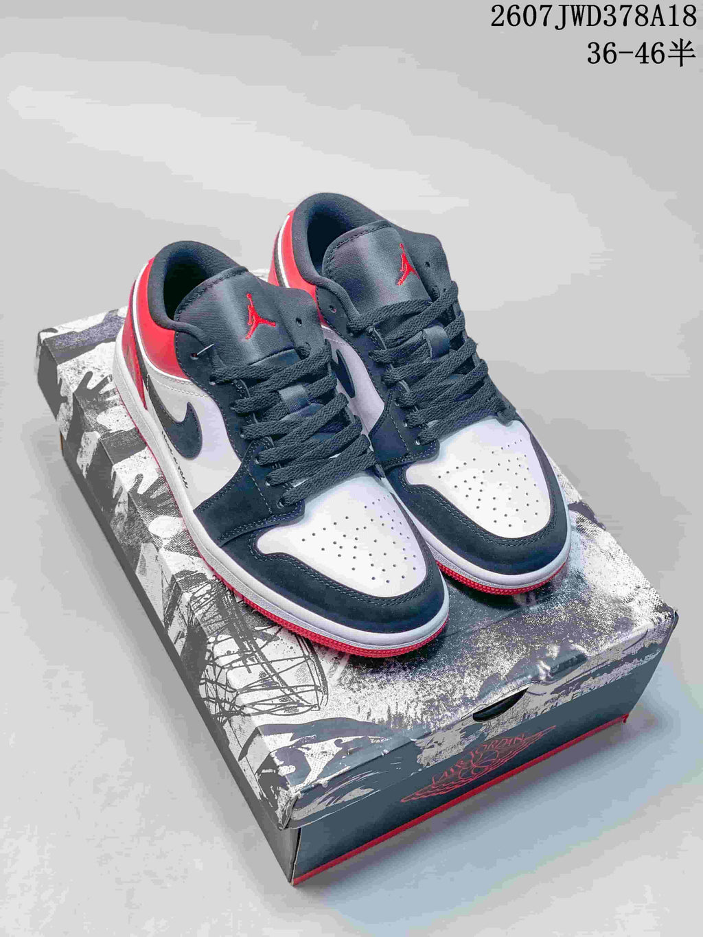Pair of black, white, and red low-top sneakers displayed on a graphic shoebox