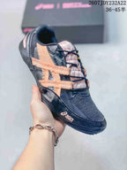 Side view of a black and peach ASICS Hypersync sneaker showing layered side detailing and a low-top profile.