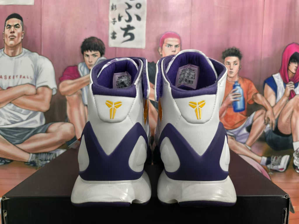 Rear view of white and purple Kobe basketball sneakers with gold heel logos; size label visible inside.