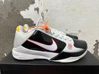 Side view of a white and black Nike Kobe basketball shoe with a red-outlined Swoosh and Zoom sole branding.
