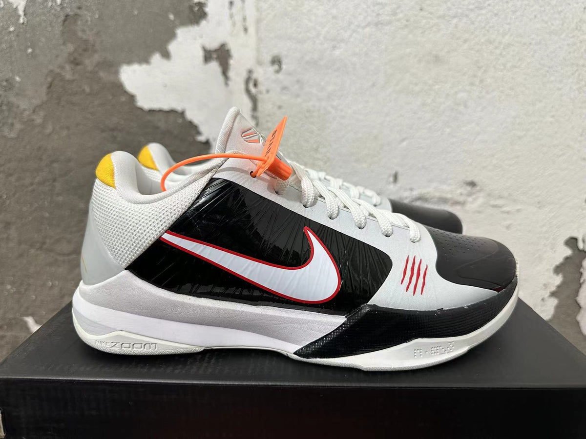 Side view of a white and black Nike Kobe basketball shoe with a red-outlined Swoosh and Zoom sole branding.