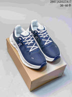 Pair of navy and white On sneakers displayed on a cardboard box, with the size range and source code visible at the top.