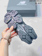 Underside view of the dark grey sneakers showing the segmented outsole and textured tread pattern.