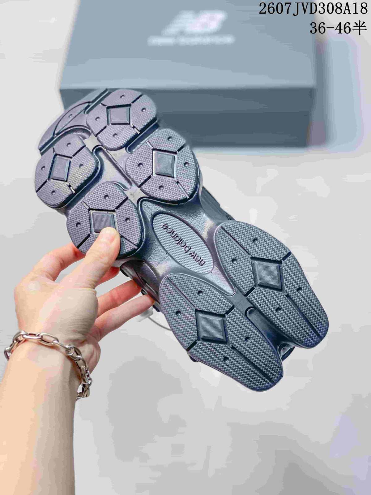 Underside view of the dark grey sneakers showing the segmented outsole and textured tread pattern.
