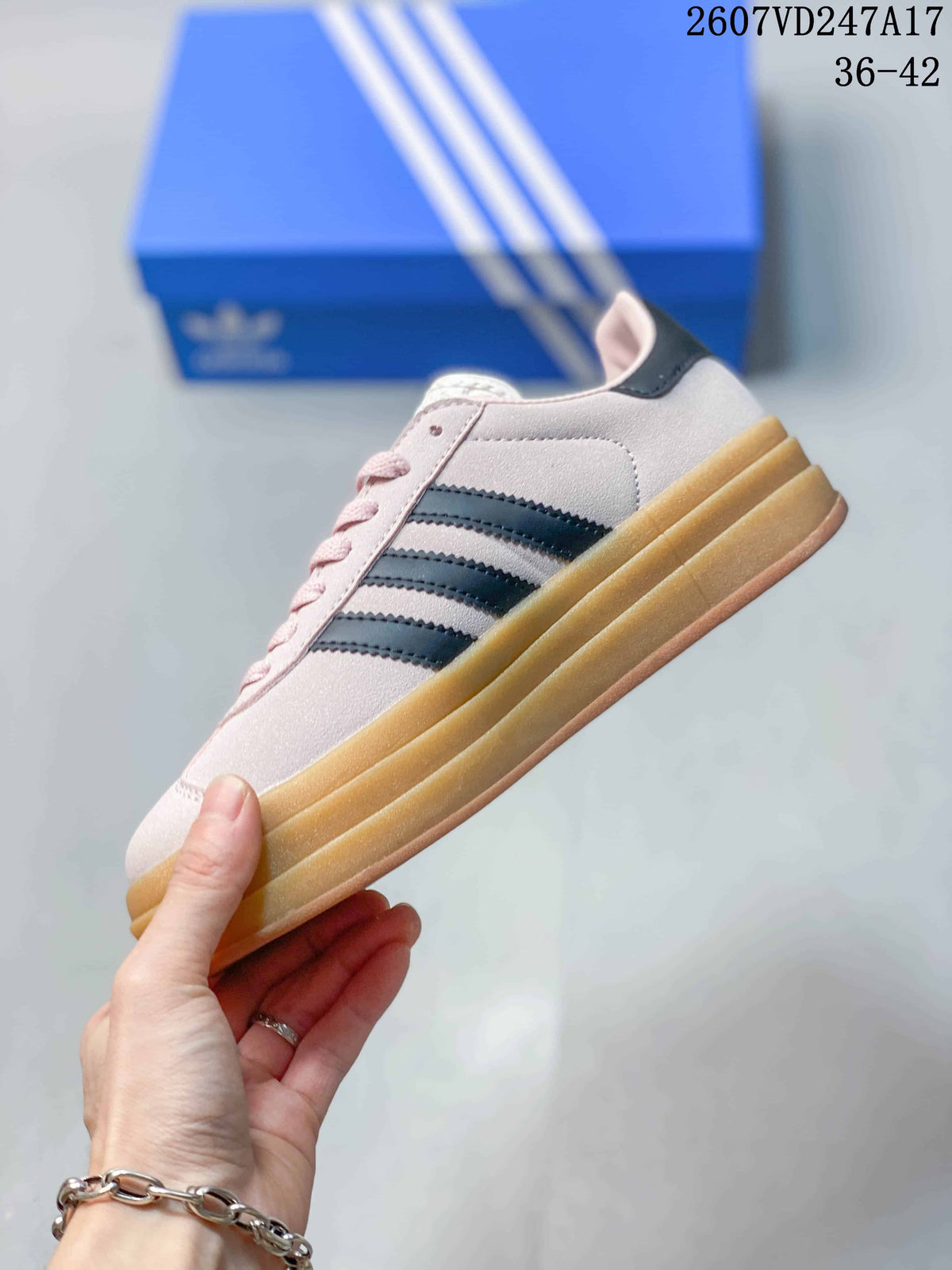 Side view showing the pale pink upper, black three stripes, and thick gum platform sole.