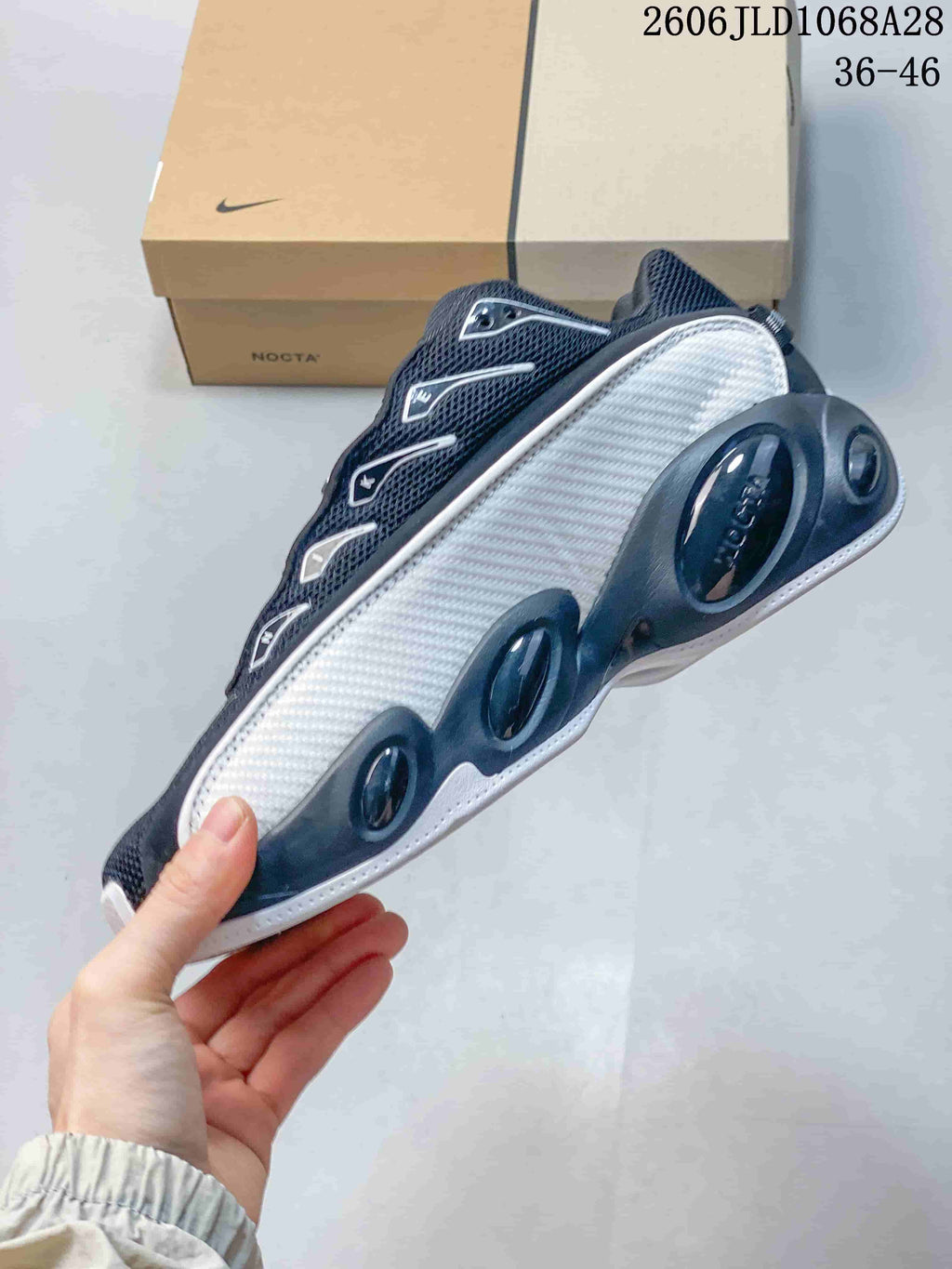 Side view of a black and white Nike NOCTA Glide sneaker with sculpted side panels.