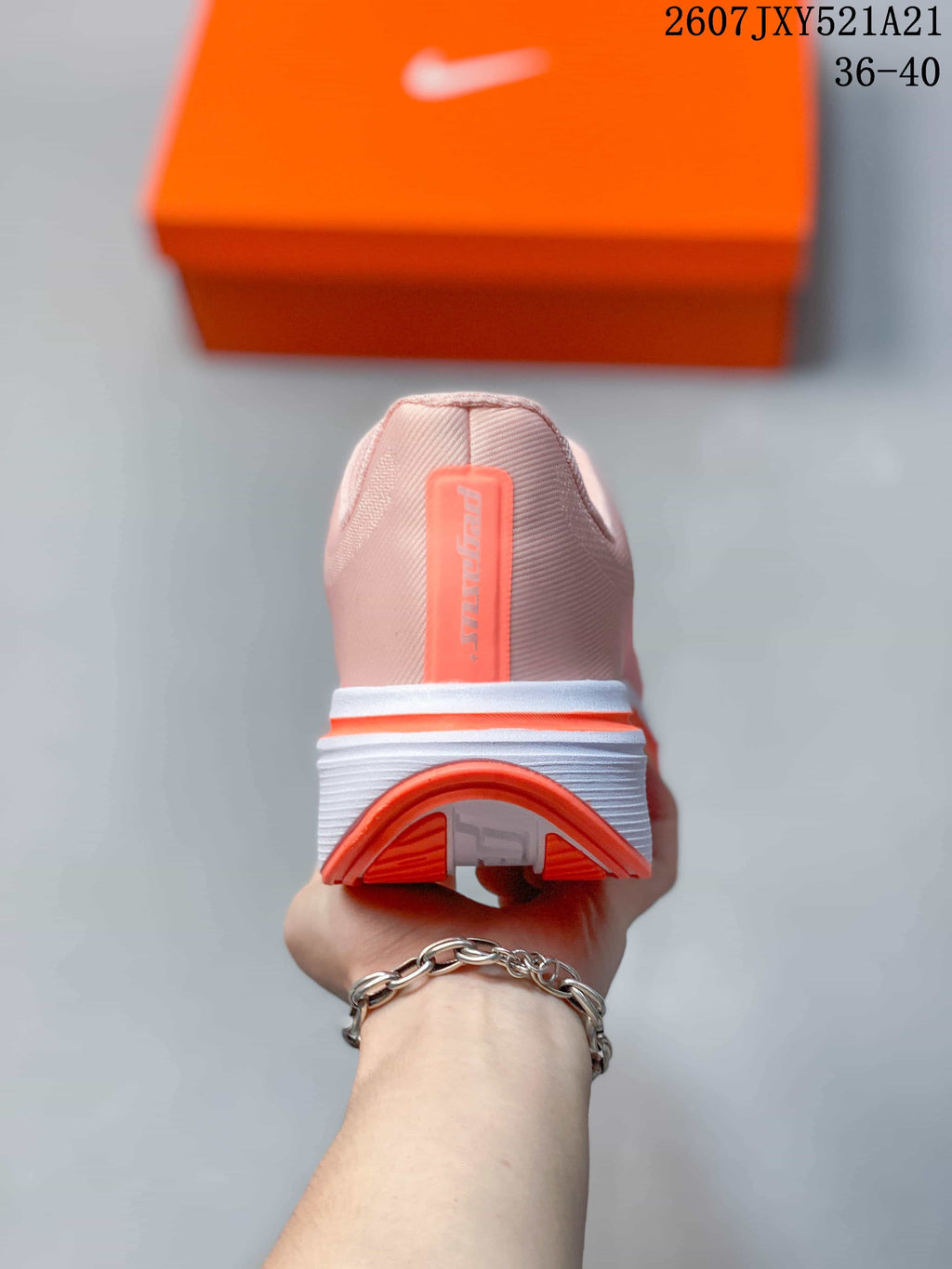 Rear view of a pale pink sneaker showing the heel construction, coral outsole edge, and vertical Pegasus branding.