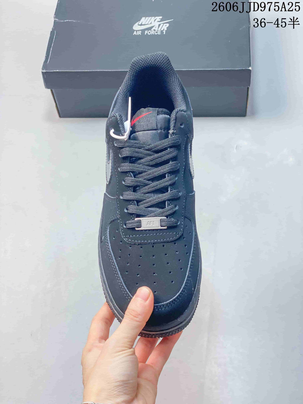 Top view of the black sneaker showing the perforated toe box, lace-up closure, tongue, and metal lace accessory.