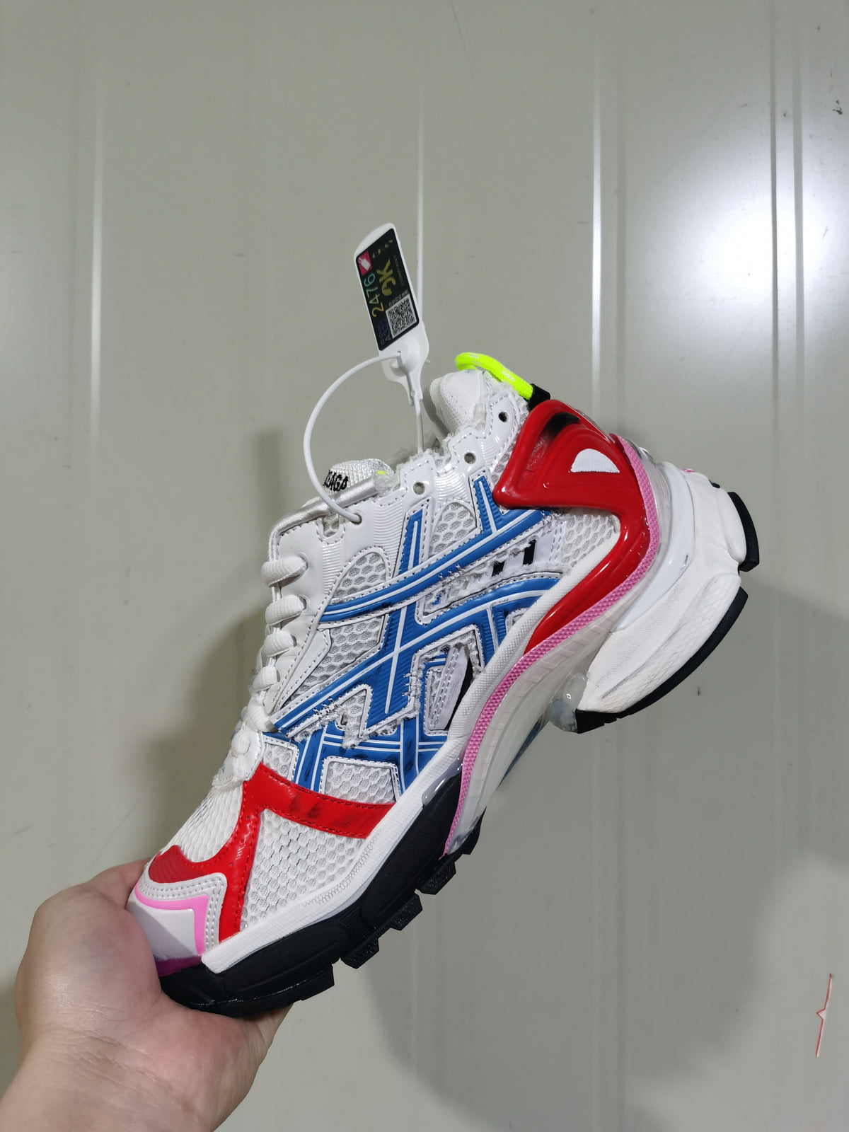Angled view of the white Puma Runner sneaker showing the blue side branding, red toe and heel overlays, pink trim, and black outsole.