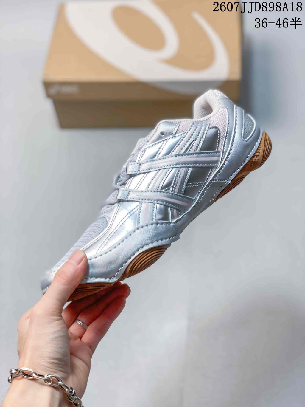 Side profile showing the silver layered upper, mesh panels, lace system, and gum-colored outsole.