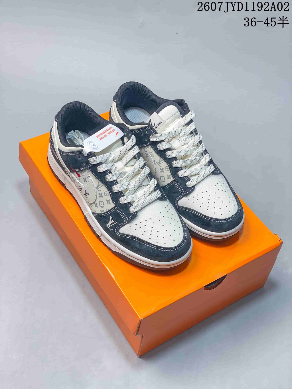 Pair of white and navy low-top sneakers with monogram-style panels and patterned laces