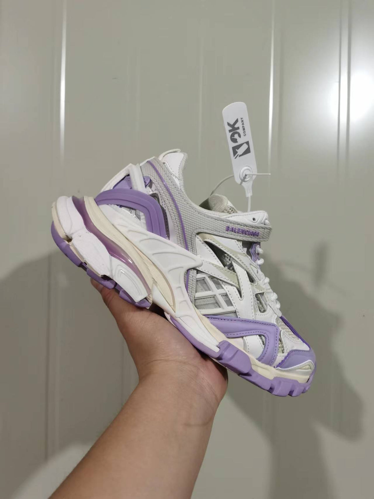 Balenciaga Track 2.0 open sneaker shown from a rear three-quarter angle in lilac, beige and grey.
