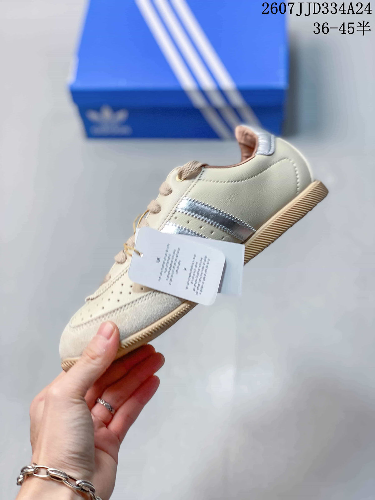 Side profile showing the cream upper, silver stripe details, beige laces, and attached product tag.