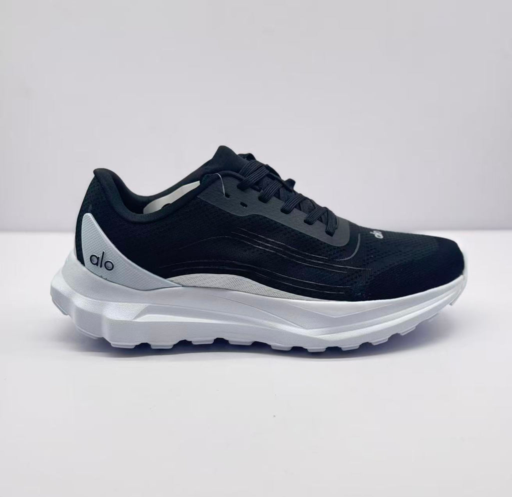 Side view of a black Alo runner sneaker with a white sole and heel panel.
