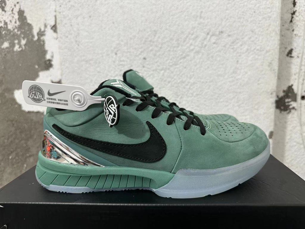 Side view of a green Nike Kobe basketball shoe with a black side logo and translucent-looking outsole.