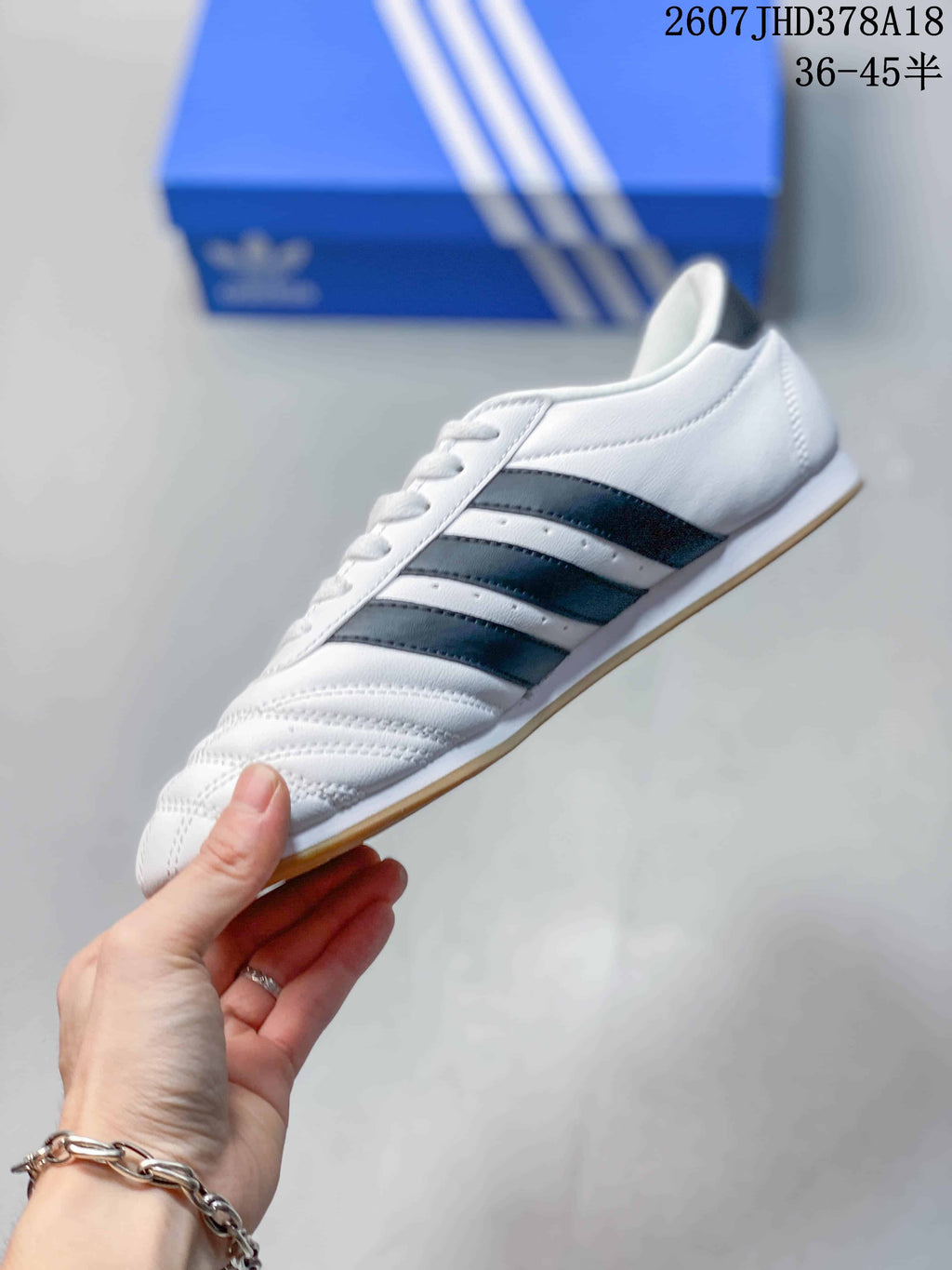 Side profile showing the white upper, black three-stripe detailing, lace-up front, and gum outsole.