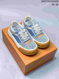 Pair of blue and white Louis Vuitton Tilted low-top sneakers displayed on an orange shoebox.