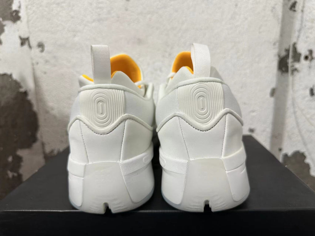 Rear view of white Adidas Dame 9 shoes with yellow lining accents