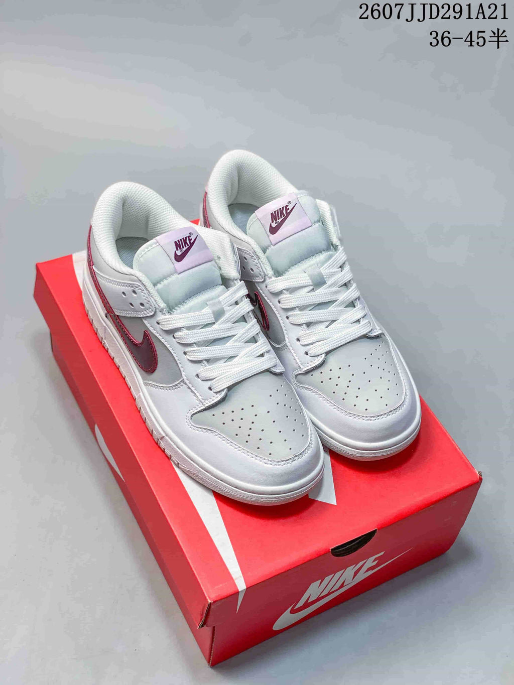 Pair of white and red Nike low-top sneakers displayed on a red shoebox, with the style code and size range visible above.